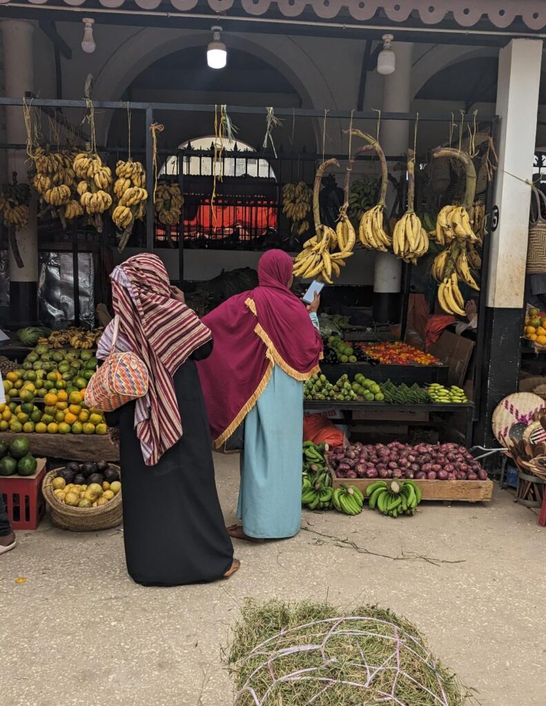 Zanzibar Holiday - Local Tanzanian women buying fresh produce in Zanzibar market - Happy Irish Wanderers