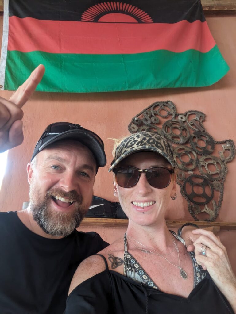 Tanzania To Malawi By Bus - Kevin + Kate with the Malawi Flag - Happy Irish Wanderers