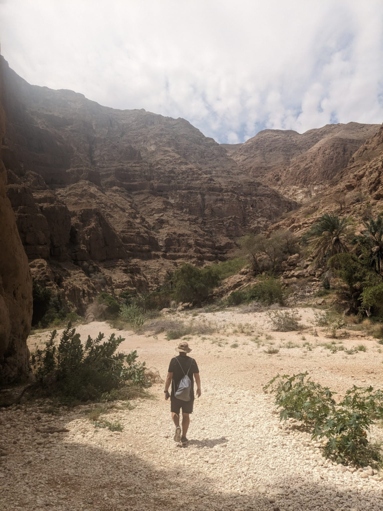 Kevin walking through a dry wadi Oman Weather - The Best Time to Visit Happy Irish Wanderers