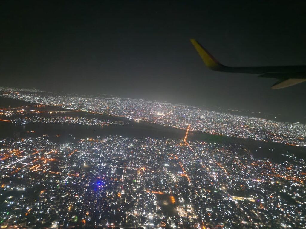 In flight view of lit up city How to Use Booking.com Flights - Happy Irish Wanderers