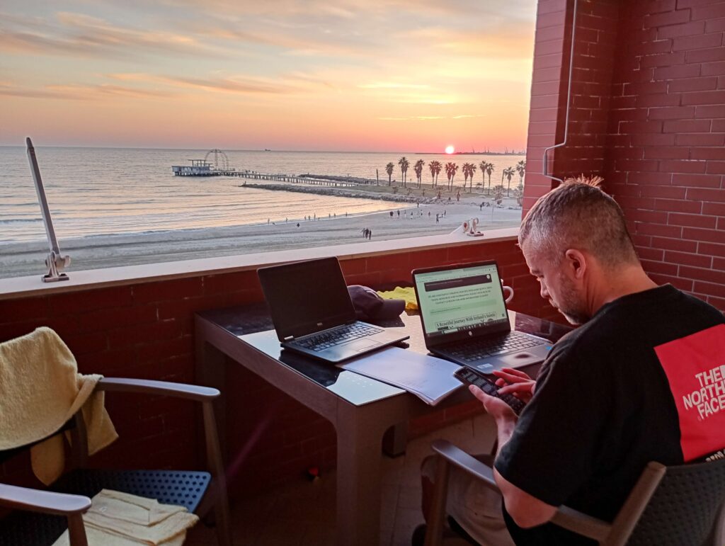 Working on laptops on beachfront apartment balcony in Durres as the sun sets
